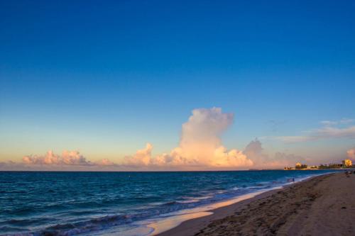 a beach with people walking on the sand and the ocean at Dream Inn PR in San Juan