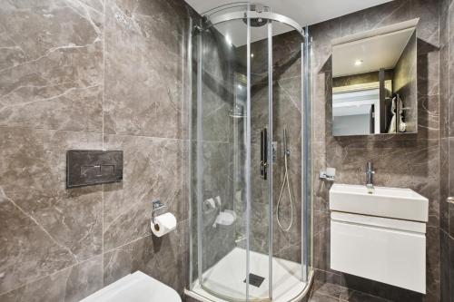 Buckingham Palace Residences by Q Apartments في لندن: حمام مع دش ومرحاض ومغسلة