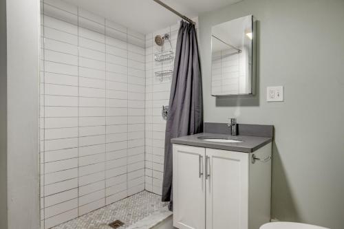 La salle de bains blanche est pourvue d'un lavabo et d'une douche. dans l'établissement Brookline 2br w public wd nr Fenway groceries BOS-909, à Brookline