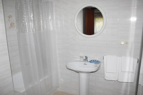 Baño blanco con lavabo y espejo en Pensión Algarrobeña, en Algarrobo