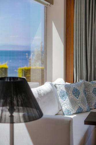 a living room with a white couch and a window at Ortunc Hotel - Cunda Island (Adult Only) in Ayvalık