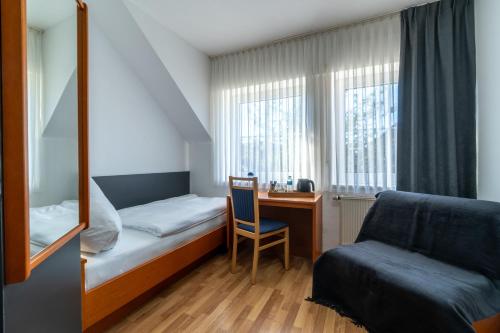 Habitación pequeña con cama, escritorio y silla. en Landhotel Elkemann, en Ahaus
