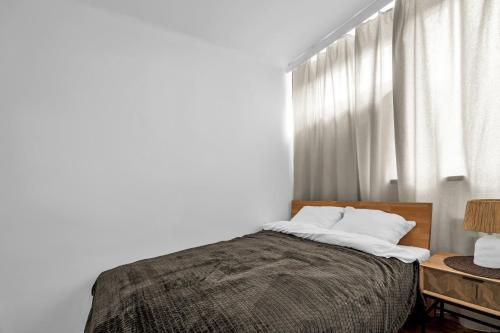 een slaapkamer met een bed met witte muren en een raam bij Jana Pawła II Comfort Apartments by Rentujemy in Warschau