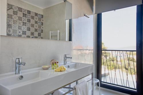 Un baño con lavabo y una gran ventana. en Spuga, en Brodarica