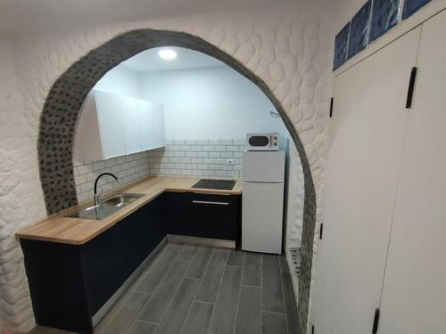 a kitchen with an archway over a sink and a refrigerator at Casa Paula in Las Playas