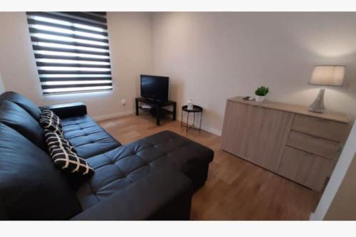 uma sala de estar com um sofá preto e uma televisão em Apartamento céntrico de diseño en calle Tres Forques,Valencia em Valência
