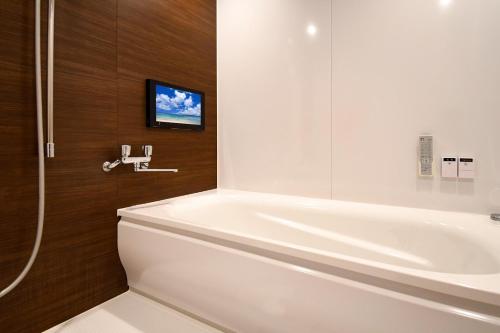 ein Badezimmer mit einer weißen Badewanne und einem Waschbecken in der Unterkunft HOTEL 31 in Funabashi