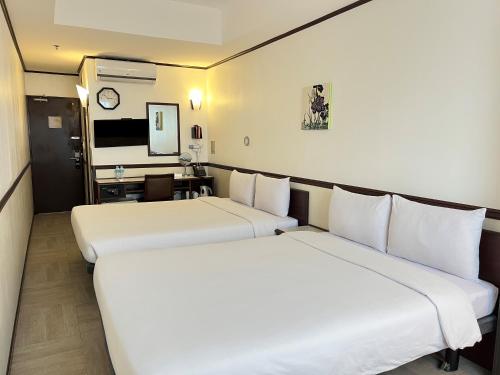 2 łóżka w pokoju hotelowym z biurkiem w obiekcie Toyoko Inn Cebu w Cebu