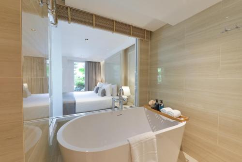 Un baño con bañera y un dormitorio. en The Beverly Hotel Pattaya, en Pattaya South