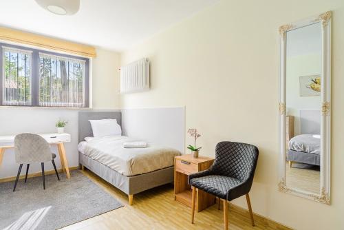 a bedroom with a bed and a mirror and a chair at P&O Apartments Juhasów - Wawer in Warsaw