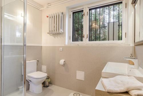 a bathroom with a toilet and a sink and a window at P&O Apartments Juhasów - Wawer in Warsaw