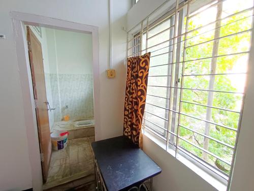a bathroom with a window with a bench next to it at Ajanta Lodge in Guwahati