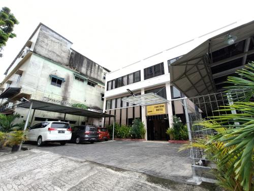 a parking lot with cars parked in front of buildings at RedDoorz at Fortune Hotel Jalan Walanda Maramis Manado in Manado
