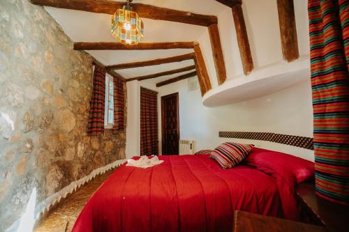 sypialnia z czerwonym łóżkiem w pokoju w obiekcie Los Chozos w mieście Benaocaz
