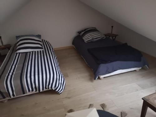 a bedroom with two beds and a wooden floor at Le petit Plessis studio in Ruaudin