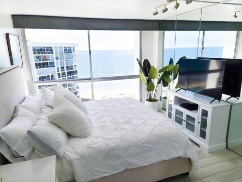a bedroom with a white bed and a television at Luxury Beach-Front High-Rise Apartment in San Diego