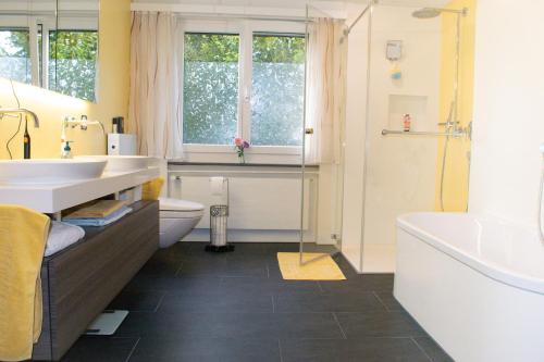een badkamer met 2 wastafels, een bad en een toilet bij Waldparadies in Neftenbach I Winterthur Nummer 1 in Neftenbach