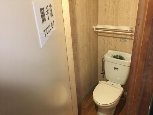 千曲市にある亀清旅館の小さなバスルーム(トイレ付)、壁に看板が備わります。