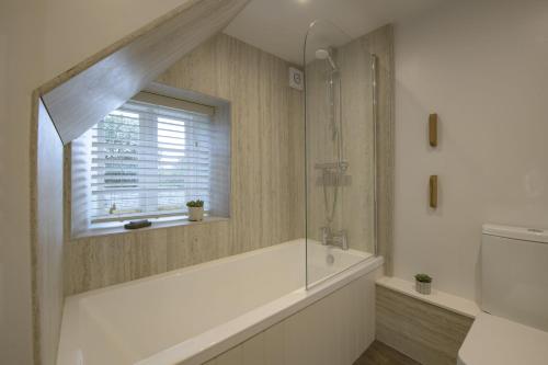 a bathroom with a bath tub and a window at Penny Pot Cottage in Middleham