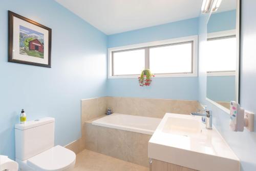 a bathroom with a tub and a toilet and a sink at Queenstown Modern Studio at Arthurs Point in Queenstown