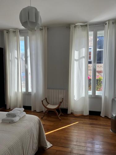 - une chambre avec des rideaux blancs et un lit avec une chaise dans l'établissement Le Lys, à Épernay
