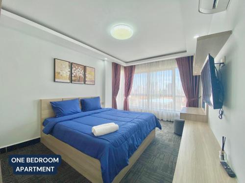 een slaapkamer met een bed met blauwe lakens en een televisie bij WH Chamkarmon Residence in Phnom Penh