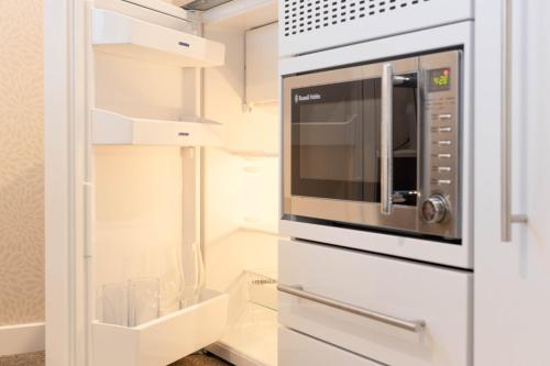a kitchen with a microwave in a white kitchen at Queenstown Modern Studio at Arthurs Point in Queenstown