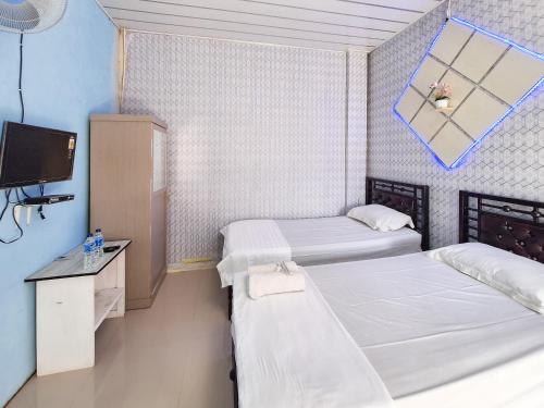 a room with two beds and a tv in it at Homestay Sakinah Syariah Mitra RedDoorz in Bukittinggi