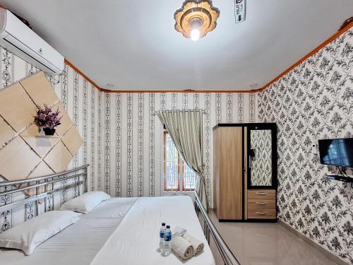 1 dormitorio con 1 cama y TV en la pared en Homestay Sakinah Syariah Mitra RedDoorz en Bukittinggi