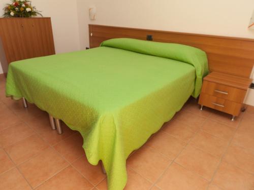 a bed with a green blanket on top of it at B&B La Collina in Vasto