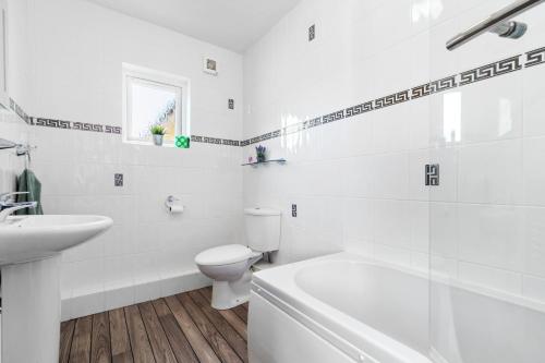 a white bathroom with a toilet and a sink at St Helens Apartment 1 - Short Walk to Beach in Amroth