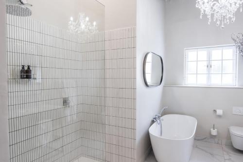 biała łazienka z wanną i umywalką w obiekcie Laborie Jonkershuis w mieście Paarl