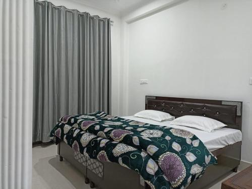 a bedroom with a bed with a comforter and pillows at RADHA BNB ( HOMESTAY ) in Dharamshala