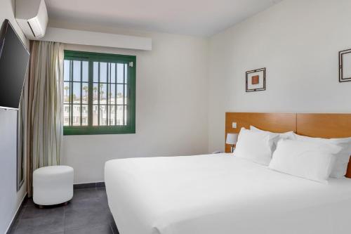 a bedroom with a large white bed and a window at Club del Carmen in Puerto del Carmen