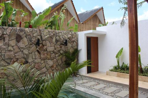 a house with a stone wall and a swimming pool at Astakaia Cottage in Ciwidey