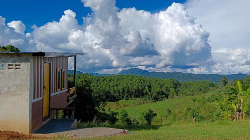 a house on a hill with a view of the mountains at ไร่นิธิสุนทร nithisoonthon farmstay in Mae Hong Son