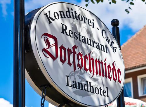 ein Schild für ein Restaurant an der Seite eines Gebäudes in der Unterkunft Landhotel Dorfschmiede Konditorei-Café-Restaurant in Höchenschwand