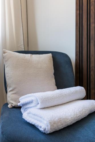 two white towels sitting on a blue chair with a pillow at SARAH - Design Studio Lumineux Bergson in Saint-Étienne