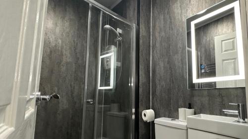 a bathroom with a shower and a toilet and a sink at The En-Suite Escape. 4-Bed Luxury Stay in Castleford