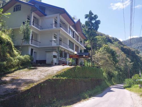 a building on a hill next to a road at Norbulingka Retreat in Gyalzing