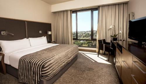 a hotel room with a bed and a flat screen tv at Southern Sun Hyde Park Sandton in Johannesburg