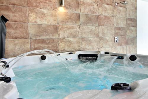 een jacuzzi in een badkamer met blauw water bij Longère avec piscine intérieure, spa, sauna in Douarnenez