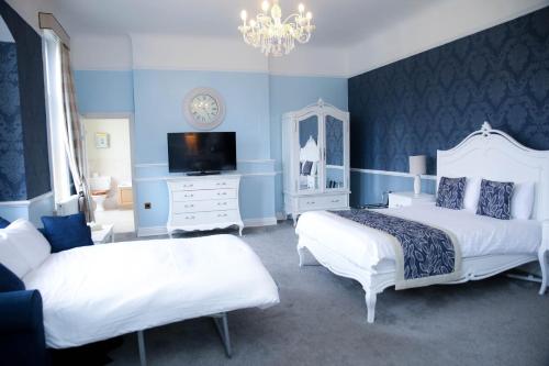 a blue bedroom with two beds and a tv at Shendish Manor Hotel & Golf Course in Hemel Hempstead