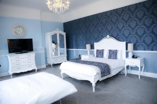a blue bedroom with two beds and a tv at Shendish Manor Hotel & Golf Course in Hemel Hempstead