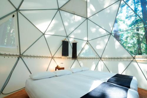 una camera con un letto in una stanza con pareti in vetro di 泊まれる公園 INN THE PARK a Numazu