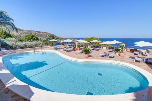 uma piscina com cadeiras e guarda-sóis e o oceano em Hoposa Costa D'or - Adults Only em Deia