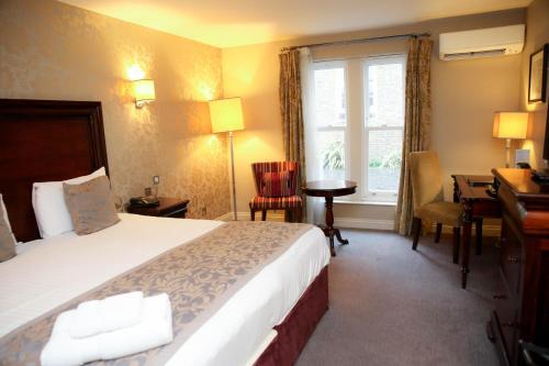 a hotel room with a bed and a desk and a window at Shendish Manor Hotel & Golf Course in Hemel Hempstead