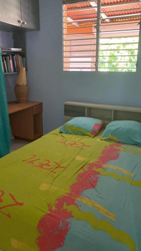 a bed with a colorful comforter on top of it at Location de meublés in Morne-à-lʼEau