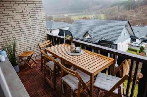 einen Holztisch und Stühle auf dem Balkon in der Unterkunft Ferienwohnung mit Seeblick — Sport und Erholung in Winterberg