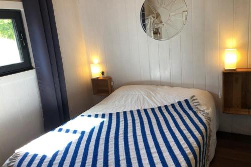 a bedroom with a bed with a blue and white striped blanket at Charming House In Pornichet Near The Beach in Pornichet